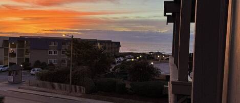 A view of a residential street during sunset with buildings and a clear sky.