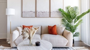 Ein Wohnzimmer mit einer Couch, einem Couchtisch, einer Lampe und einer großen Pflanze.