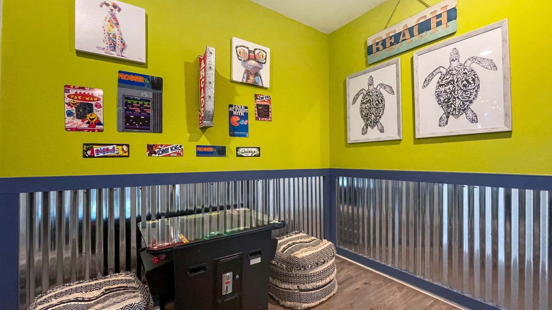 A room with a vibrant yellow wall, a metal-framed window, and various framed pictures including a turtle illustration.