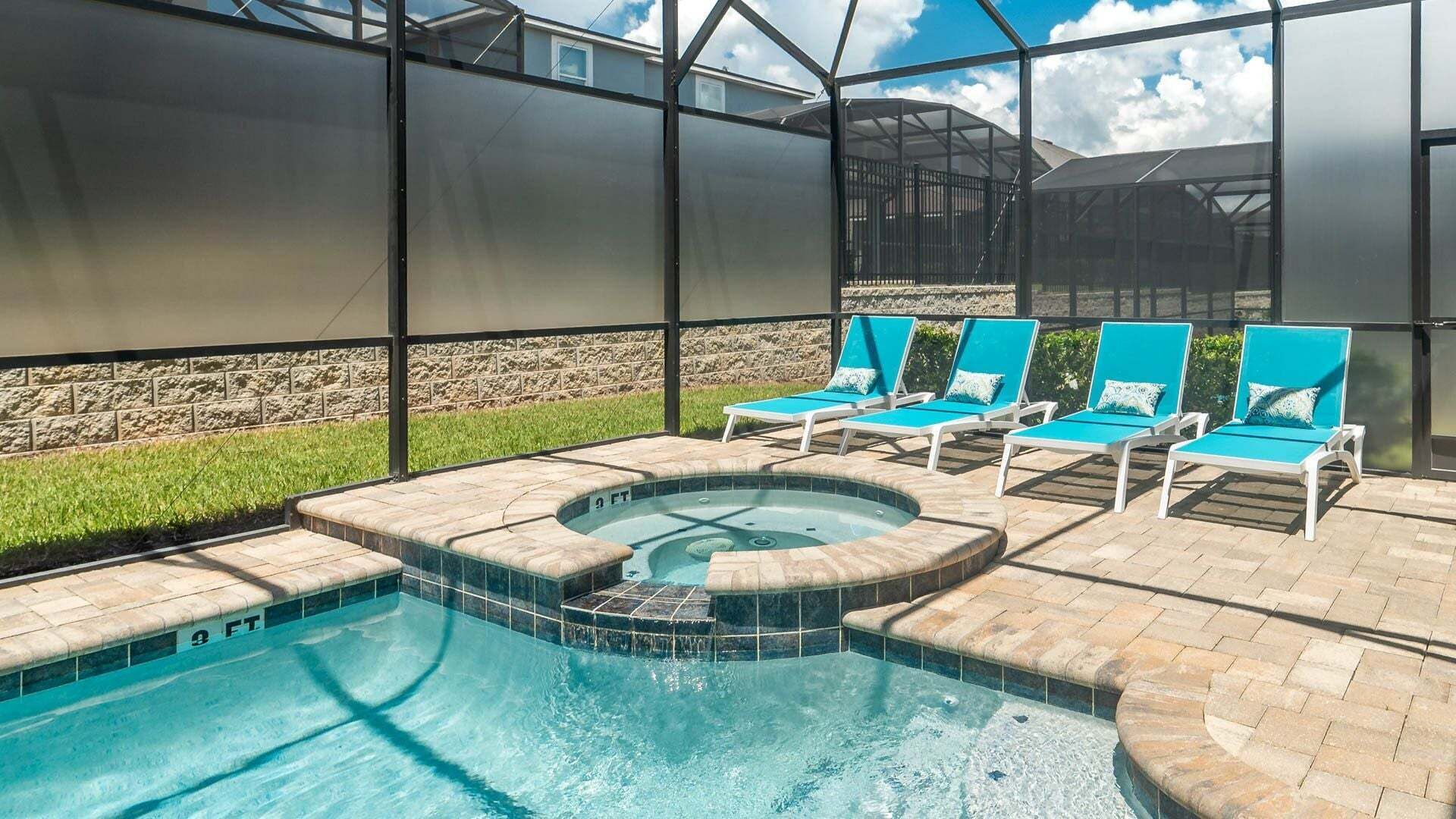 Une piscine dotée de chaises longues et d’un jacuzzi, le tout entouré d’une structure en verre.