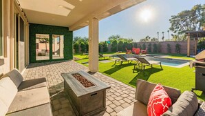 Un patio couvert avec une piscine, du mobilier d’extérieur et un foyer.