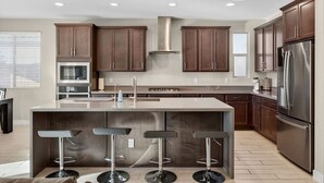 Une cuisine moderne dotée d’un îlot central, d’appareils électroménagers en acier inoxydable et d’armoires en bois.