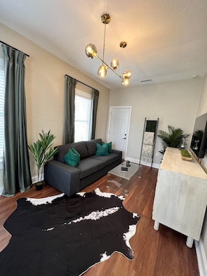 A modern living room with a sofa, a coffee table, a cowhide rug, and a dining area with a white table and chairs. - Updated Condo in Heart of Tampa 1578 (Tampa)