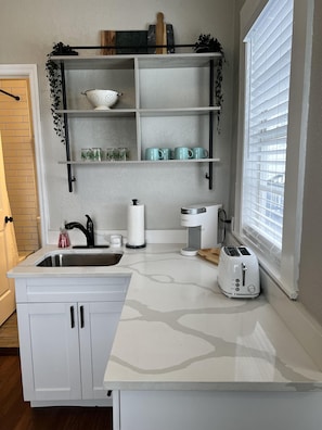 A modern kitchen with white cabinetry, a stainless steel sink, a coffee maker, and a toaster. - Updated Condo in Heart of Tampa 1578 (Tampa)