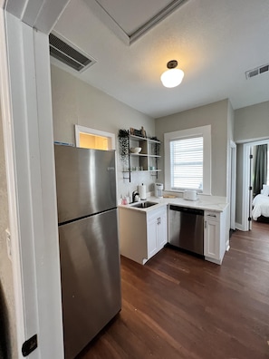 A compact kitchen with a stainless steel refrigerator, white cabinetry, and a built-in shelf with decorative items. - Updated Condo in Heart of Tampa 1578 (Tampa)
