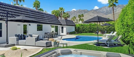 Une maison moderne dotée d’une piscine, d’un espace salon extérieur et d’un jacuzzi.