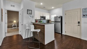 A modern kitchen with white cabinets, stainless steel appliances, and a bar area with stools. - Gdl3206 (Kissimmee)