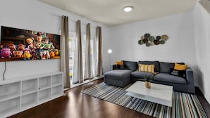 A living room with a grey sofa, a white coffee table, and a TV on the wall. - Gdl3206 (Kissimmee)
