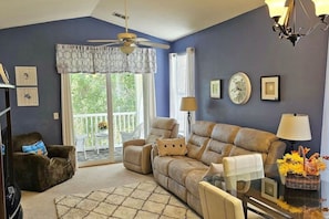 A living room with a sofa, armchairs, a ceiling fan, and a view through a large window. - Hidden Haven by WT Golf Peaceful 2BR Condo (Myrtle Beach)