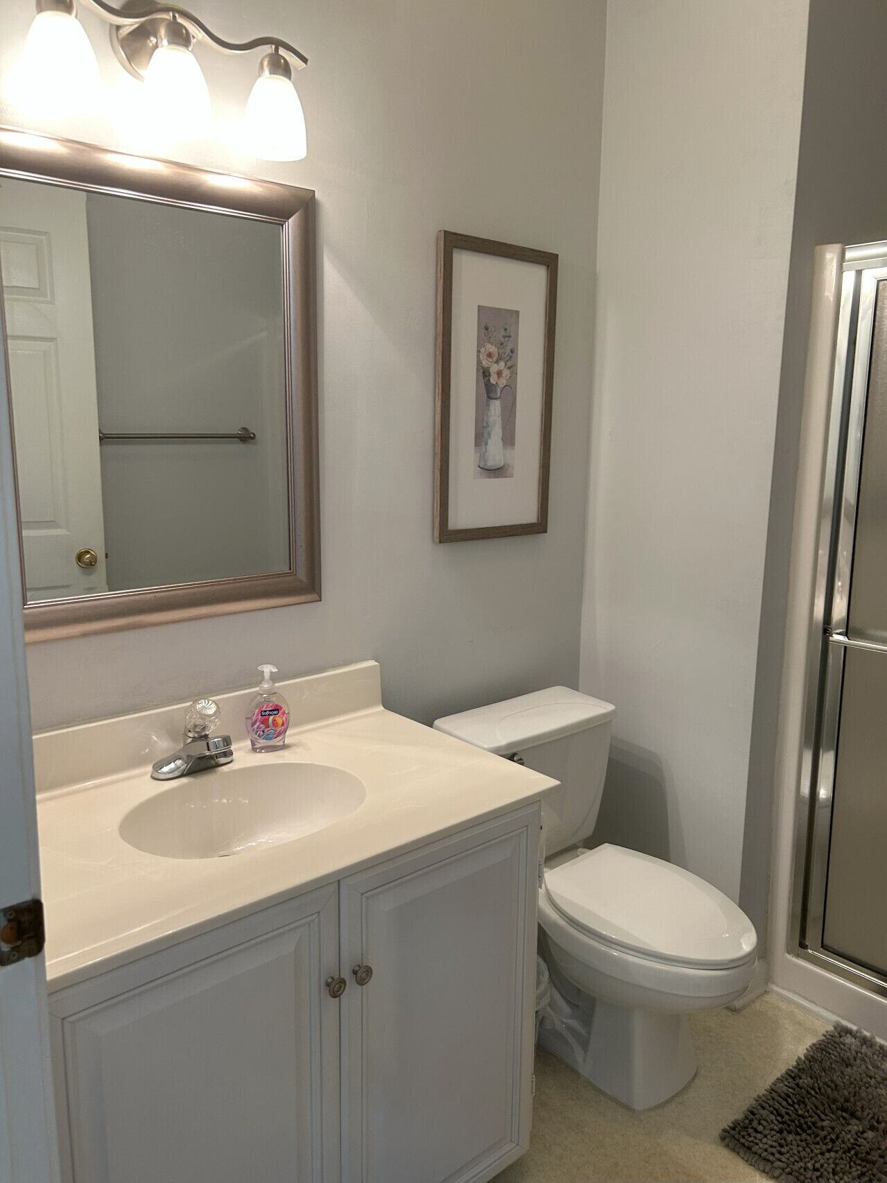 A bathroom with a white sink, a toilet, and a framed picture on the wall.