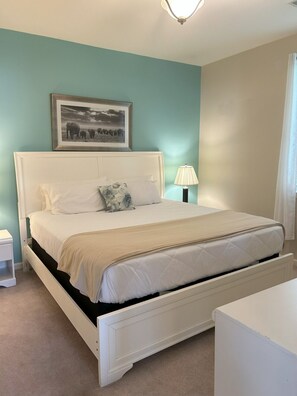 A bedroom with a bed, a nightstand, a lamp, and a framed picture on the wall. - Hidden Haven by WT Golf Peaceful 2BR Condo (Myrtle Beach)