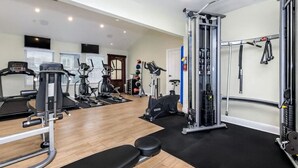 Ein Fitnessstudio mit Laufbändern, Krafttrainingsgeräten und einer Trainingsbank.