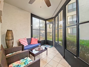 A sunlit room with a sofa, chairs, and a coffee table. Large windows provide a view of the outdoors. - Bay Oaks - D41 (Siesta Key)