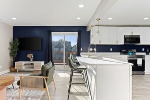 A modern kitchen with white cabinets, a black stove, and a blue kettle. - Chic Boho Retreat Near Downtown (Indianapolis)
