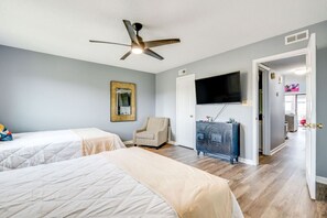 A bedroom with two beds, a ceiling fan, a TV, a chair, and a dresser. - Rhythm Retreat Bar, Patio & Space for 10 (Surfside Beach)