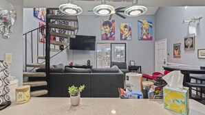 Ein modernes Wohnzimmer mit grauem Sofa, einer Treppe und einer Küchenzeile mit Arbeitsplatte.