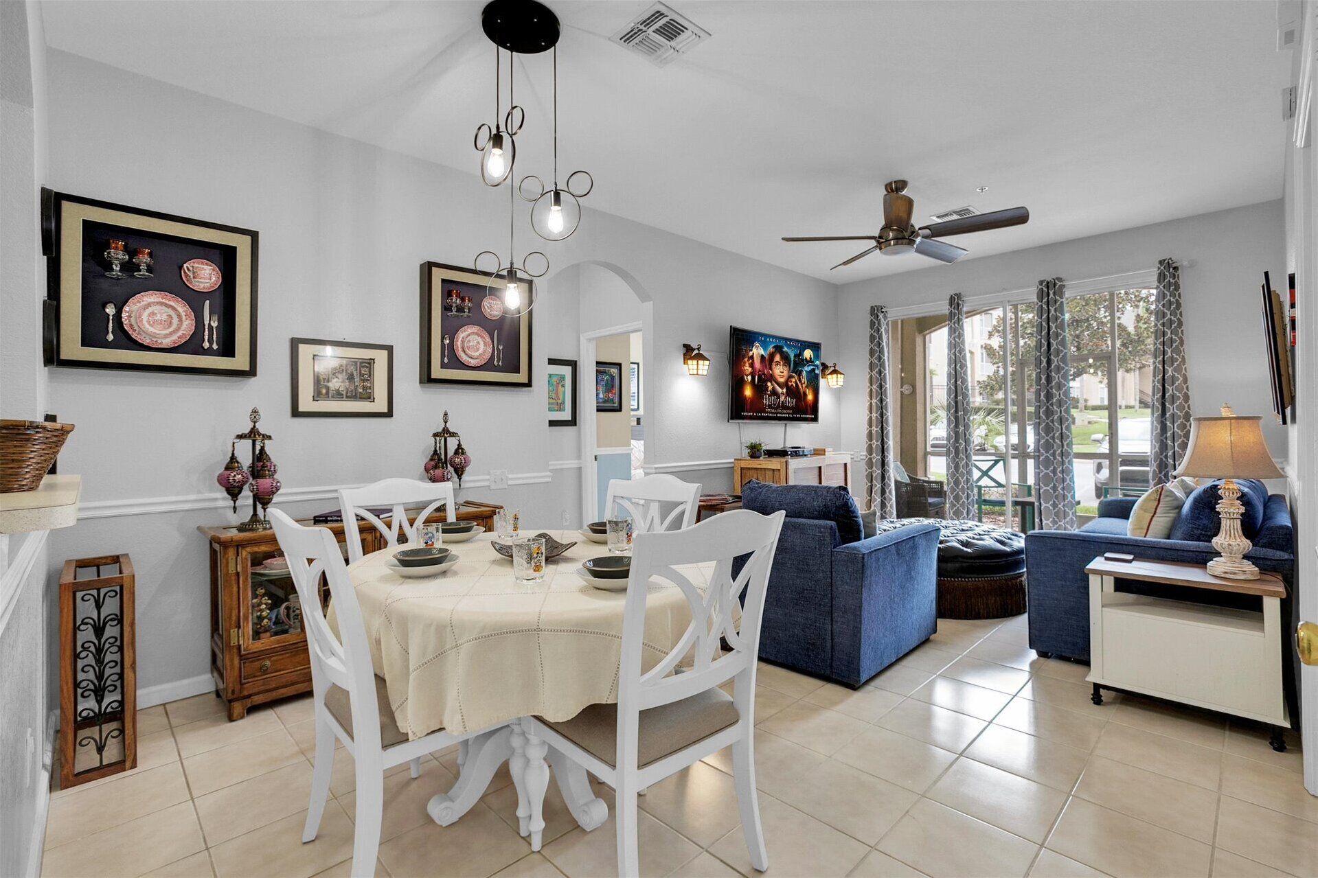 A dining area with a white table and chairs, a blue sofa, and a ceiling fan.