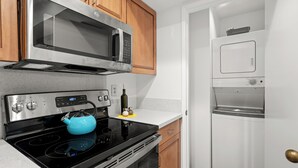 A kitchen with a microwave, stove, oven, and a white refrigerator. - Plaza Villas 615 (Palm Springs)