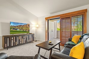A living room with a TV, a sofa, a coffee table, and a cabinet. - Plaza Villas 615 (Palm Springs)