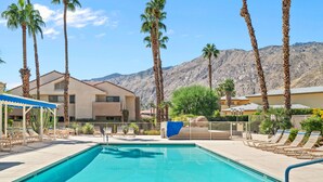 A swimming pool with lounge chairs, palm trees, and a mountain backdrop. - Plaza Villas 615 (Palm Springs)