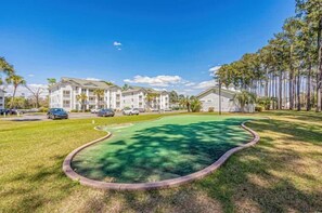 A residential building with a green lawn and a curved driveway. - River Oaks 28G (Myrtle Beach)