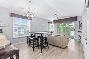 A modern kitchen with a dining area, large windows, and a balcony. - River Oaks 28G (Myrtle Beach)