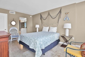A bedroom with a bed, two bedside tables, a chair, a dresser, a mirror, and a wall-mounted net. - Sands Beach Club Ph1114 (Myrtle Beach)
