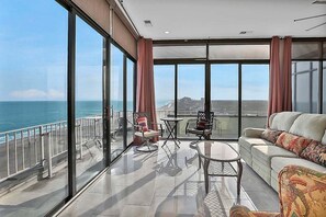 A spacious balcony with a view of the ocean, furnished with a sofa, chairs, and a small table. - Sands Beach Club Ph1114 (Myrtle Beach)