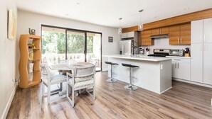 Una cocina moderna con una isla central, taburetes de bar y una mesa de comedor con sillas.