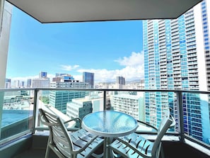 Ein Balkon mit Glastisch und Stühlen, mit Blick auf eine Skyline mit Hochhäusern.