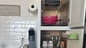 A compact kitchen with a coffee machine, dish racks, and storage cabinets. - Sun & Sand @ the Landmark Resort (Myrtle Beach)