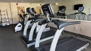 A row of treadmills in a gym with a mirrored wall and a door in the background. - Sun & Sand @ the Landmark Resort (Myrtle Beach)
