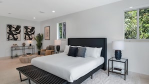 A modern bedroom with a large bed, bedside tables, a reading chair, and artwork on the walls. - Villa Granada by Rove Waterfront W/pool, Hot Tub (Miami)
