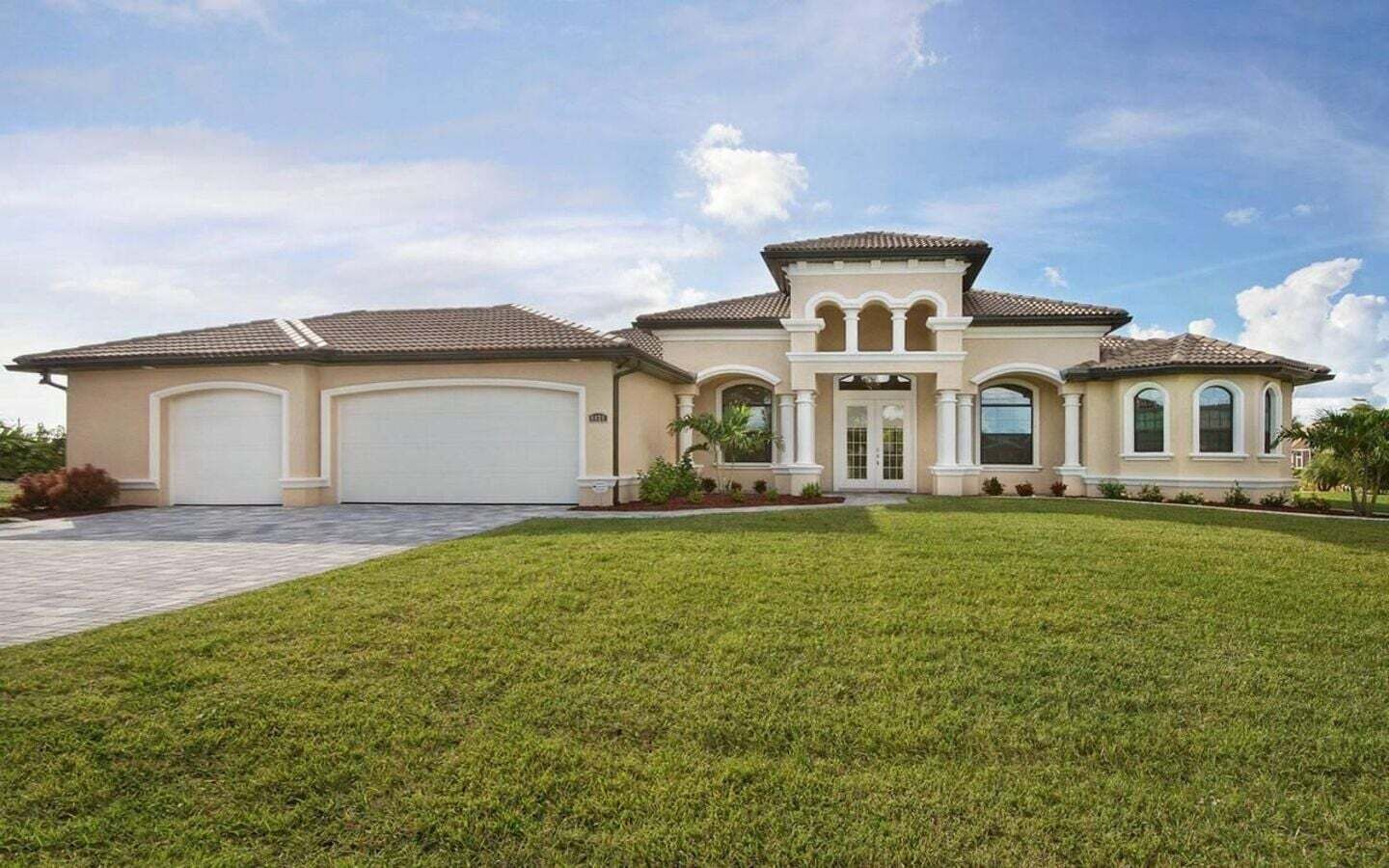 A two-story house with a large garage, a well-maintained lawn, and a clear sky.