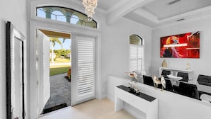 Ein modernes Interieur mit einer Kronleuchter, weißen Wänden, einem großen Fenster und einem Gemälde.