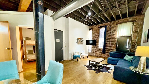 A modern living room with a brick wall, a flat-screen TV, and a blue sofa. - Nashville Rock (Nashville)