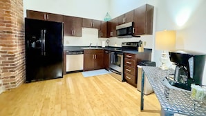 A compact kitchen with wooden cabinets, a black refrigerator, a microwave, and a coffee machine. - Nashville Rock (Nashville)