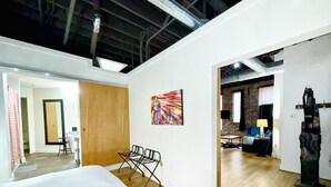 A hotel room with a large bed, a desk, and a chair. There is a painting on the wall and a sculpture on the side. - Nashville Rock (Nashville)