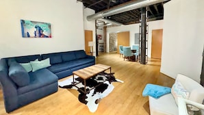 A modern living room with a blue sofa, a wooden coffee table, and a cowhide rug. - Nashville Rock (Nashville)