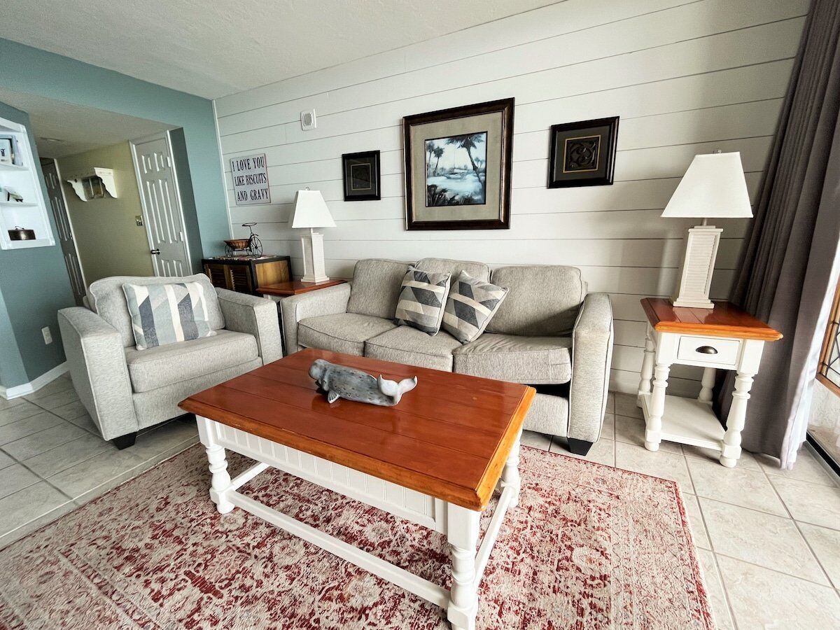 A living room with a wooden coffee table, two sofas, a white side table, and a red and white patterned rug.
