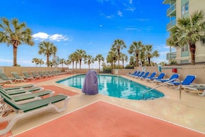 A pool area with lounge chairs, a covered seating area, and palm trees. - Ocean Forest 309 (Myrtle Beach)