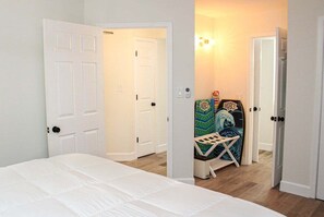 A bedroom with a bed, a white door, and a hallway leading to another room. - Ocean Forest 309 (Myrtle Beach)