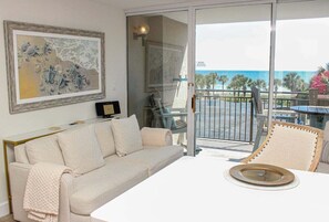 A balcony with a view of the ocean, a white table with a plate, and a beige sofa. - Ocean Forest 309 (Myrtle Beach)