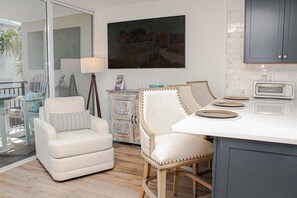 A modern kitchen with a white island, two chairs, and a cabinet. - Ocean Forest 309 (Myrtle Beach)