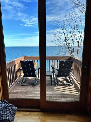 A wooden deck with two chairs and a table, overlooking a body of water. - Windsong Oasis on Lake Superior (Beaver Bay)