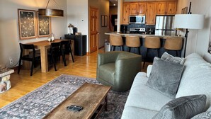 A modern living room with a sofa, a coffee table, and a dining area with chairs.