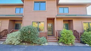 A two-story building with a front porch, a door, and a small staircase leading to the entrance.