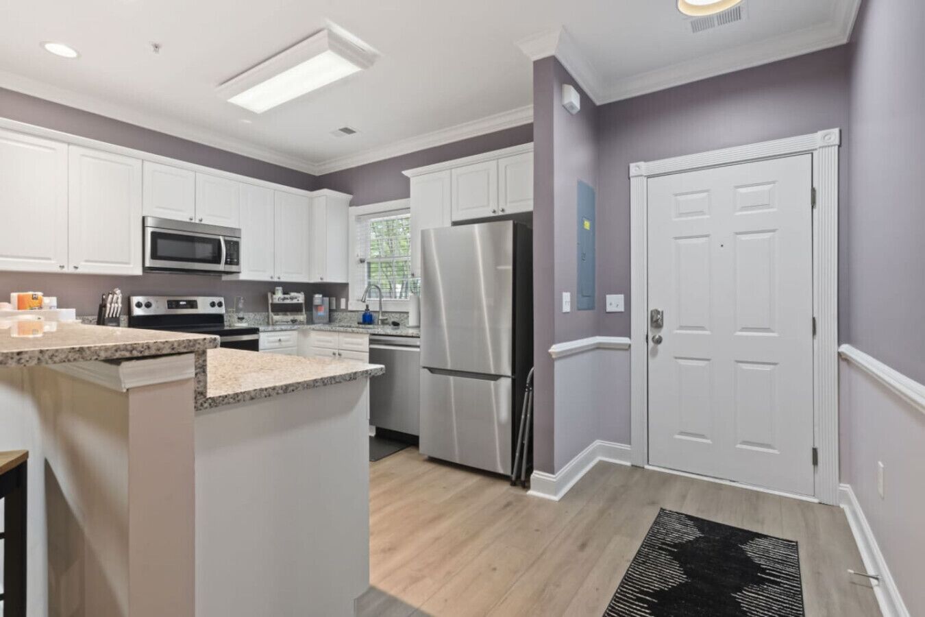 A modern kitchen with white cabinets, stainless steel appliances, and a granite countertop.