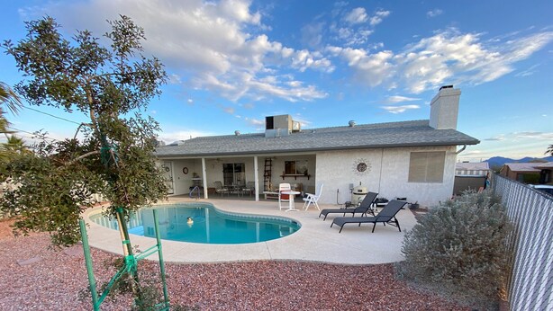 A backyard with a swimming pool, patio furniture, and a house. - Okeechobee Vacation House (Lake Havasu City)