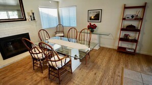 A dining area with a glass table and wooden chairs, a fireplace, and a bookshelf. - Okeechobee Vacation House (Lake Havasu City)